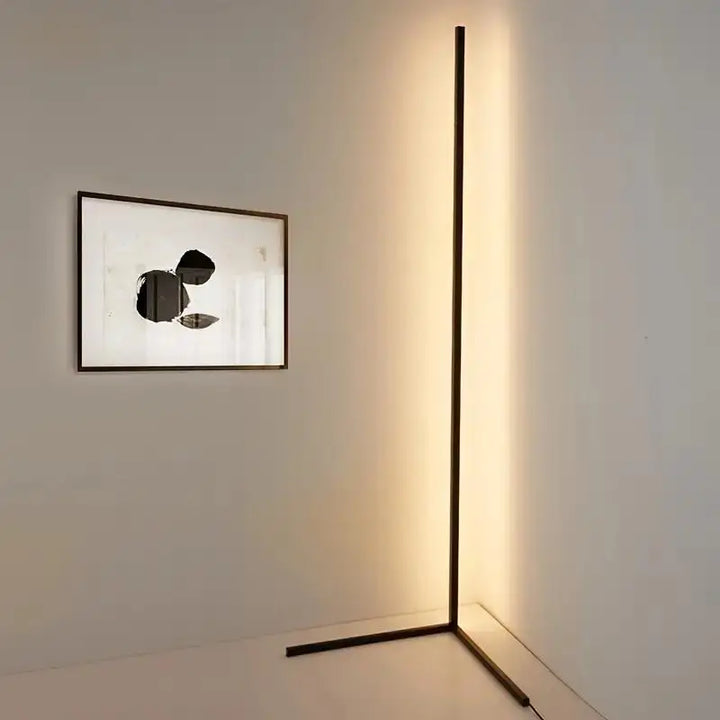 Modern floor lamp casting a long shadow on a wall with a framed abstract artwork.