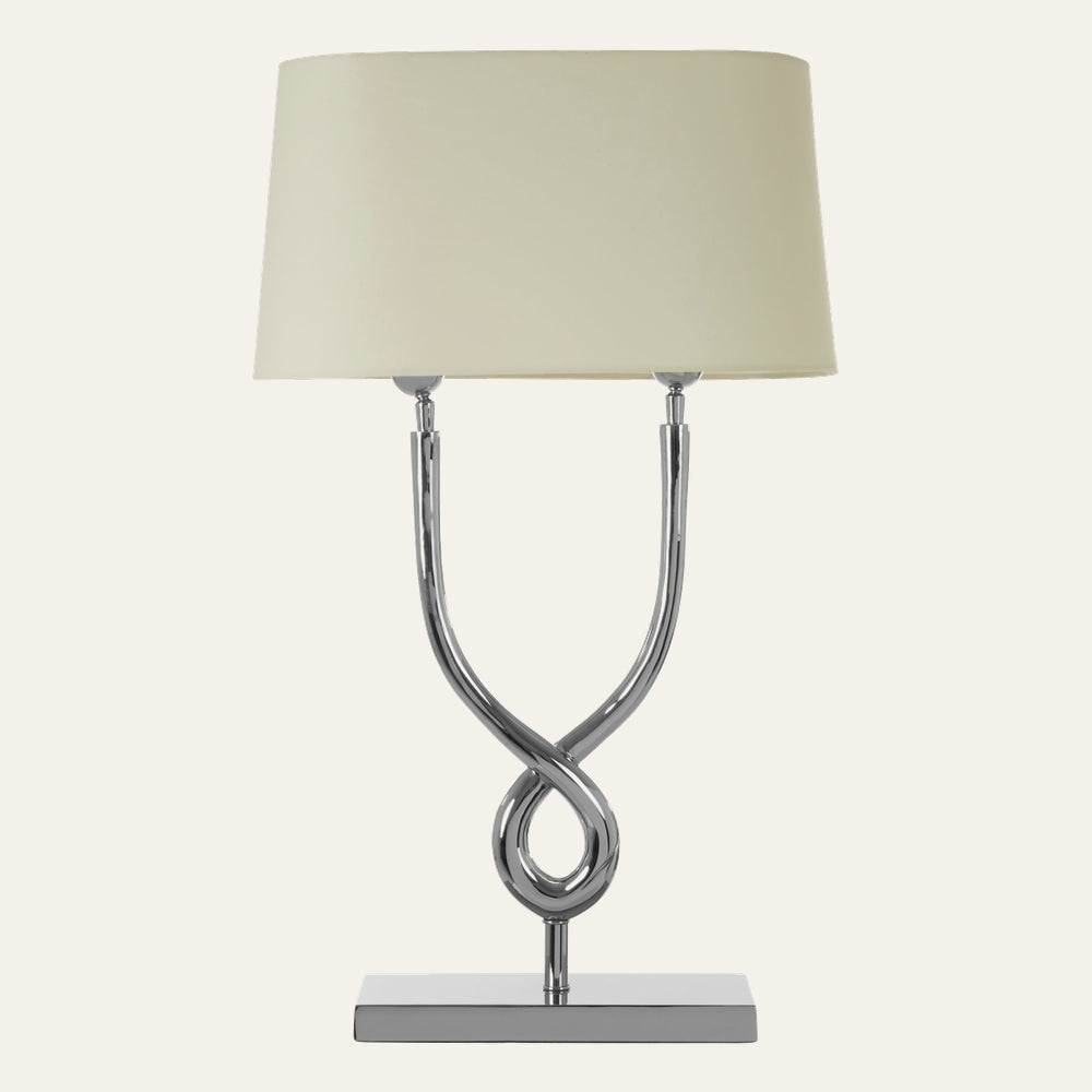 Selva Cross Base Table Lamp with polished chrome twisted cross base on a rectangular chrome platform and a cream fabric drum shade.