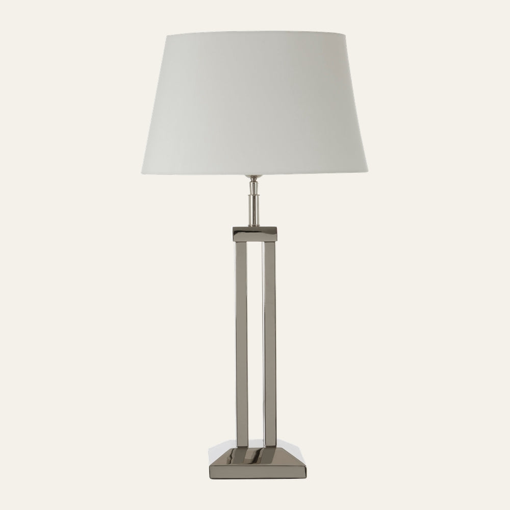 Selva Dual Rod Table Lamp with white tapered fabric shade and dual polished metal rod base on a rectangular metal pedestal