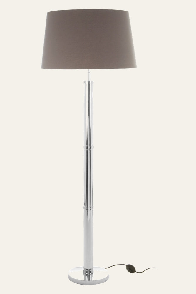 Selva Tubular Base Floor Lamp with chrome tubular column and round chrome base, brown fabric drum shade, and visible black inline foot switch on cord.