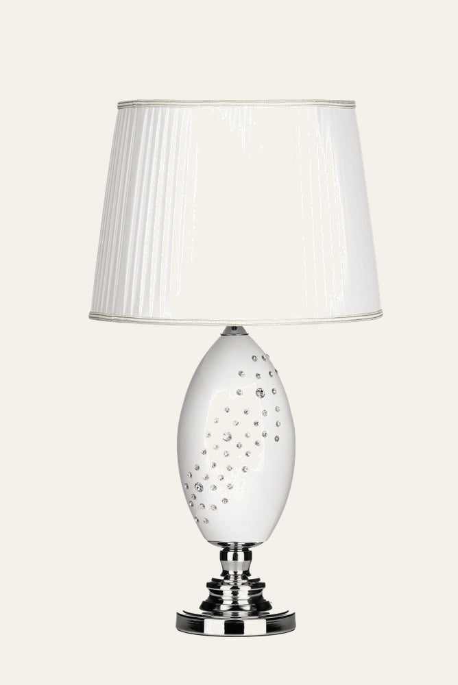 Serelle Table Lamp — glossy white oval base studded with clear crystal accents, chrome stepped round base, and white pleated fabric shade