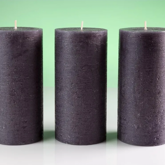 Three black candles on a white surface with a green background