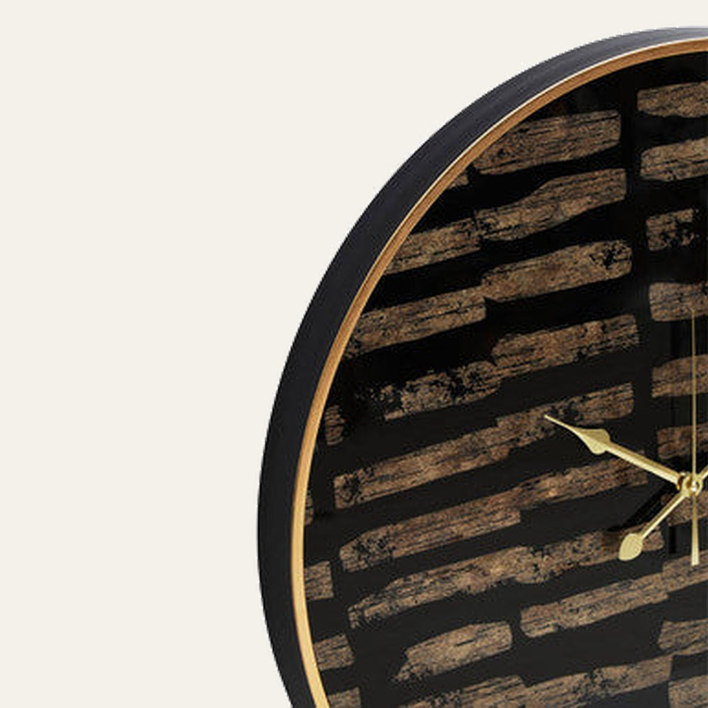 Soren Wall Clock close-up showing round black frame with gold inner rim, distressed brown wood‑effect stripe face and gold clock hands.