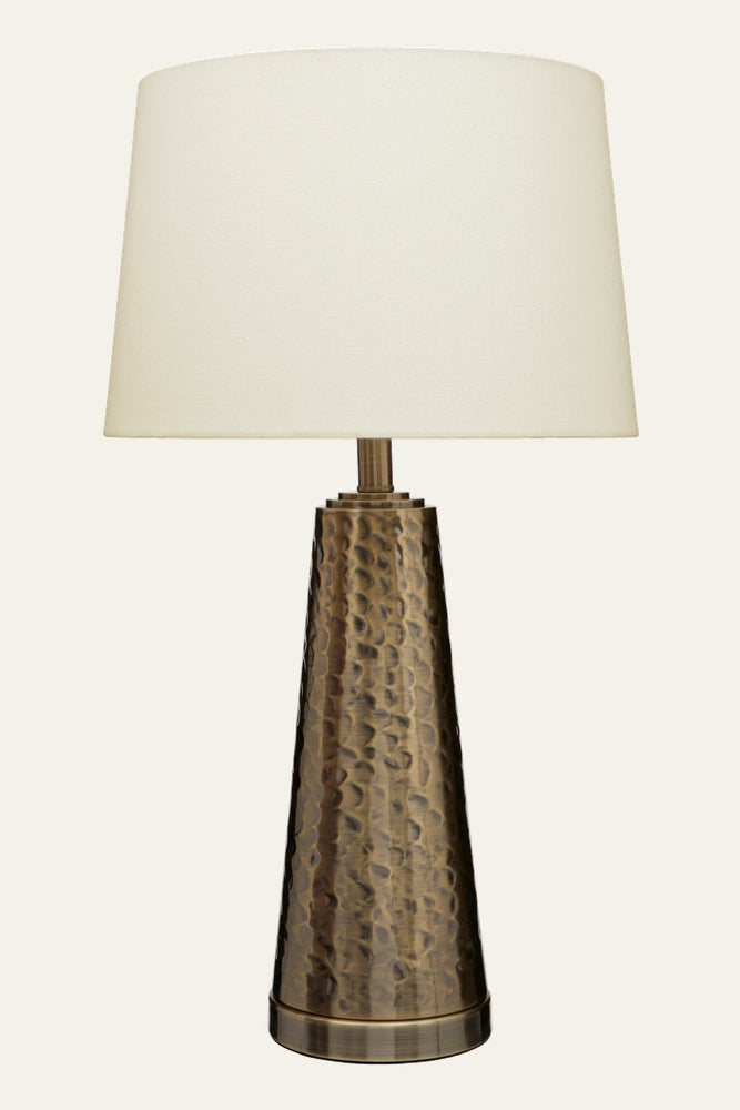 Soreva Brass Table Lamp with tapered, hammered brass base in an antique finish and a cream fabric shade