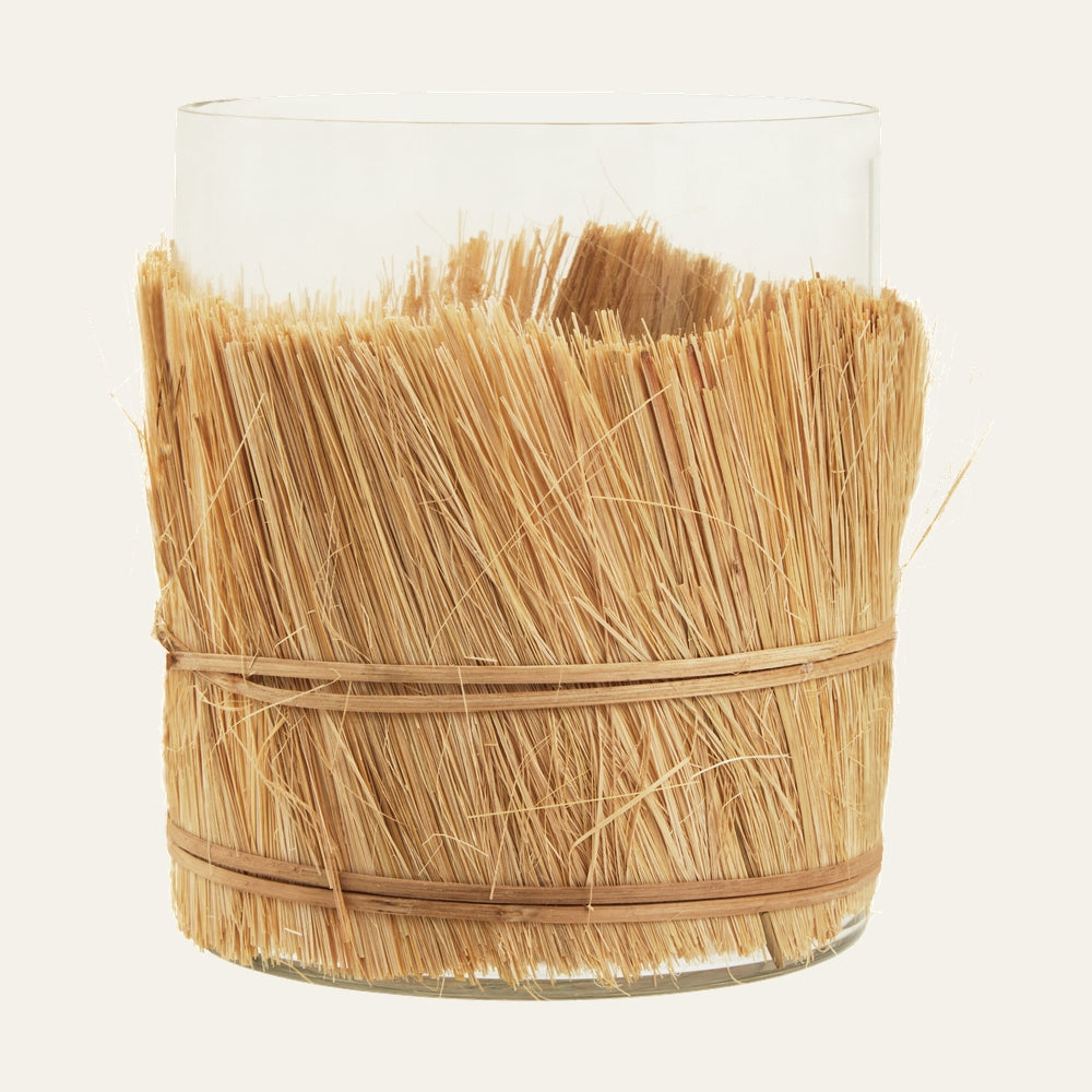 Velora Candle Holder clear glass cylinder wrapped with natural straw fringe held by two thin rattan bands