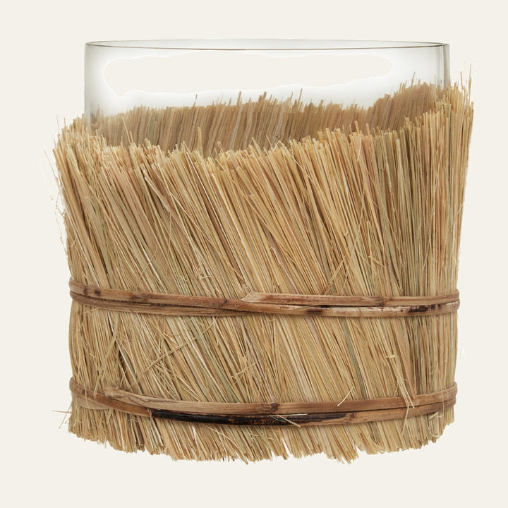 Velora Candle Holder with clear glass cylinder wrapped in natural straw fringe secured by two thin rattan bands