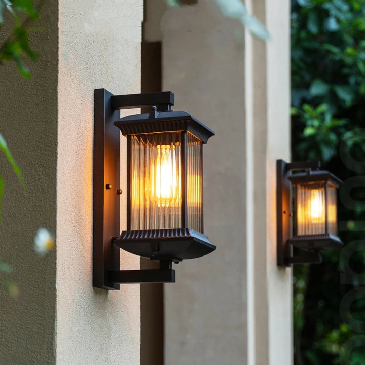 Outdoor wall lamp glowing warmly on an exterior wall at dusk